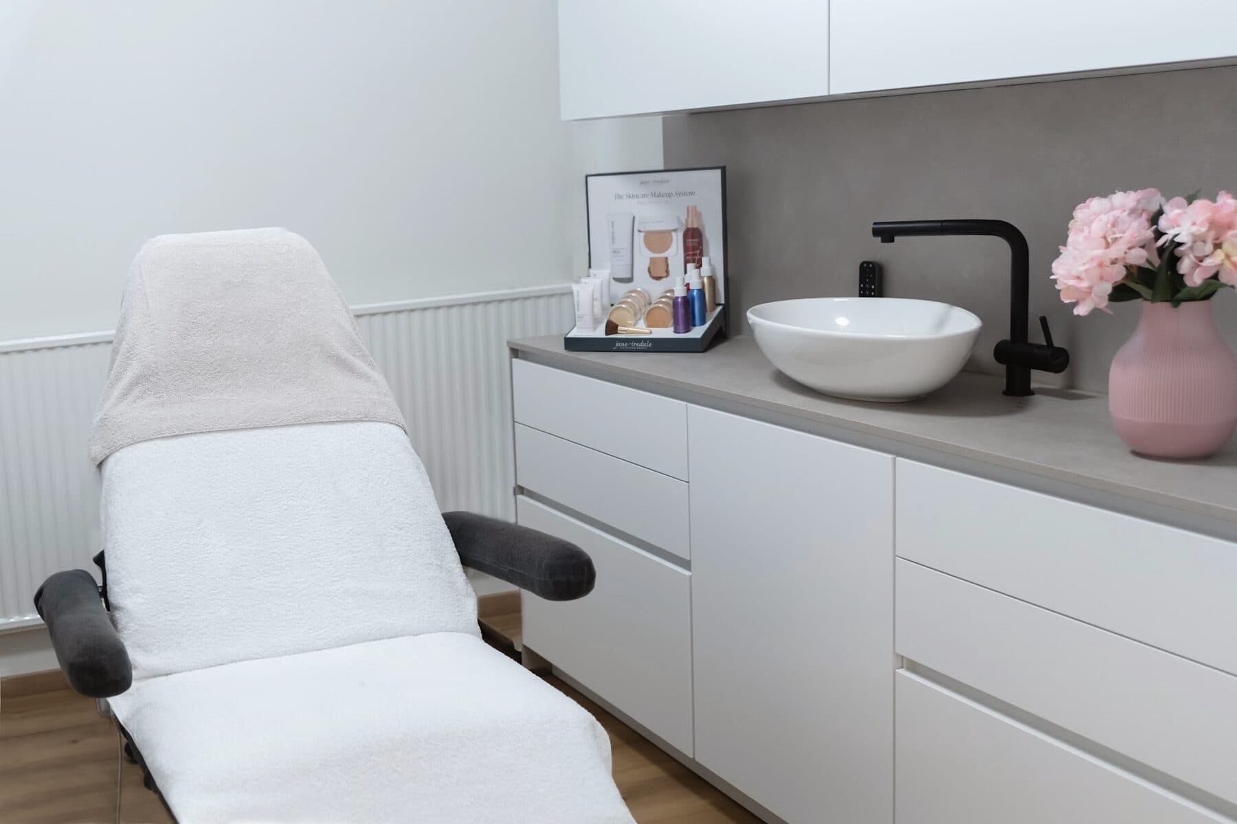 Behandlungskabine im Beautyloft mit frisch bezogener Liege, Waschbecken und Pflegeprodukten