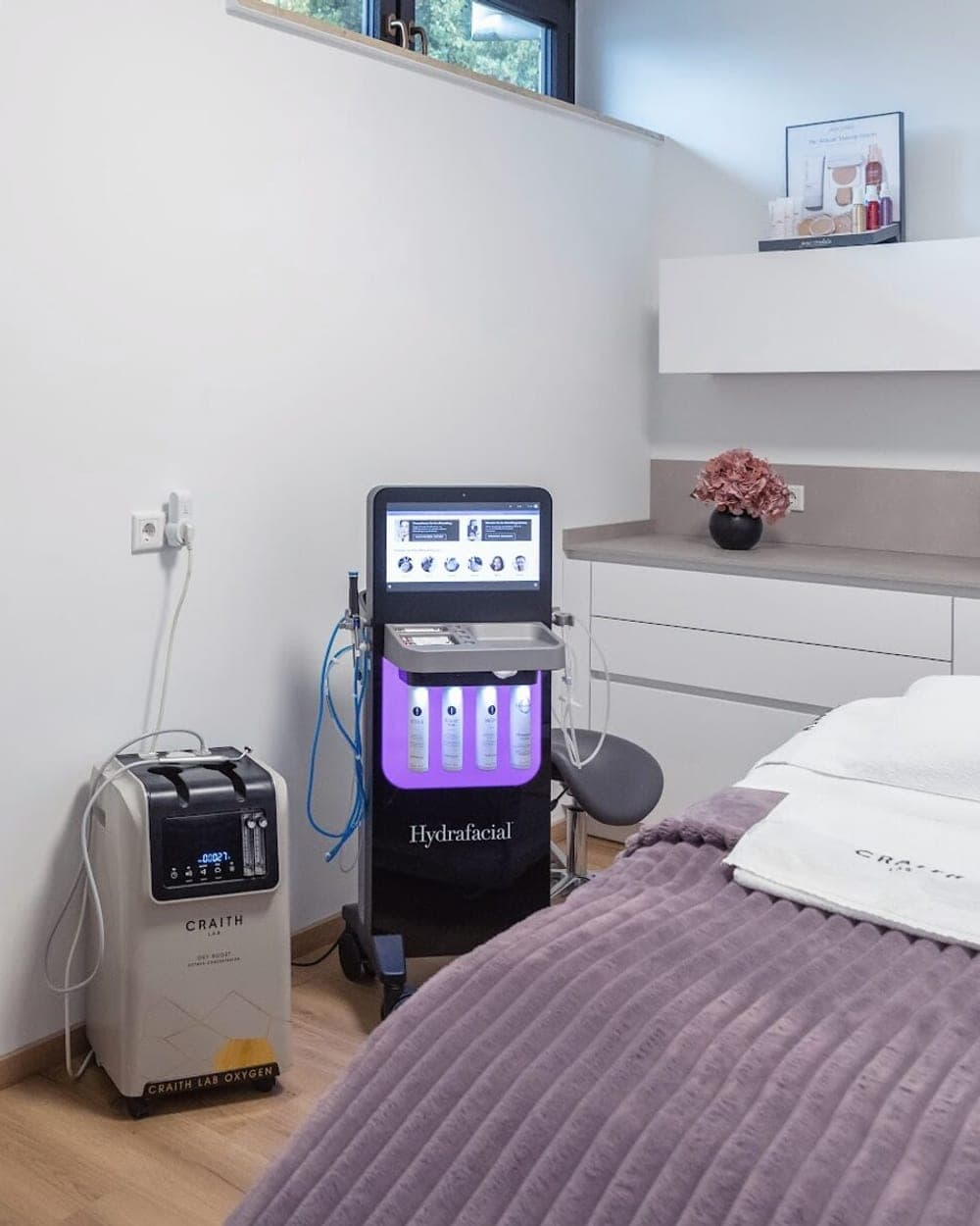 Behandlungsraum im Beautyloft mit dem HydraFacial-Gerät neben der Liege mit mauvefarbener Decke